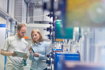 Male female supervisors digital tablet inspecting fiber optic cable in factory