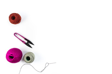 Embroidery accessories. Multicolored bundles of thread, scissors, sewing needles. White background ready for copywriting.