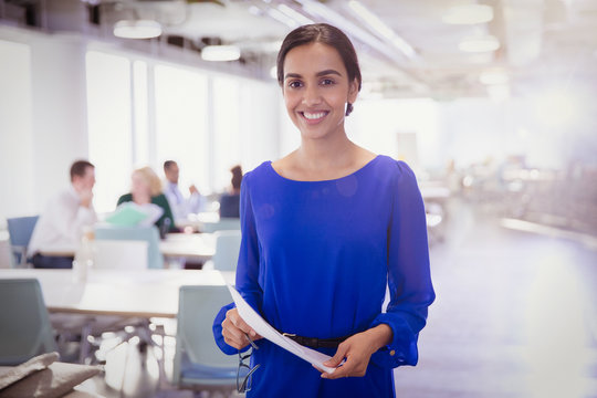 Portrait smiling businesswoman with paperwork in office