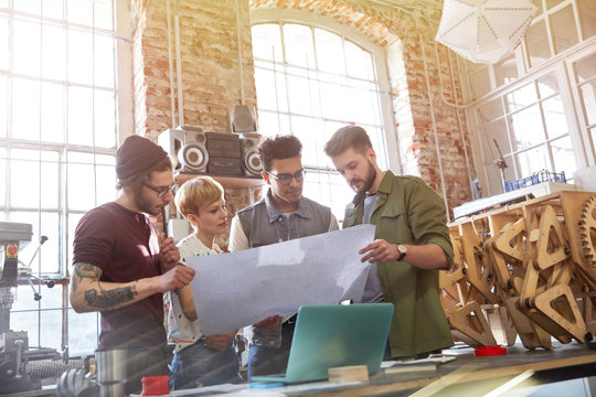 Designers examining blueprints in workshop