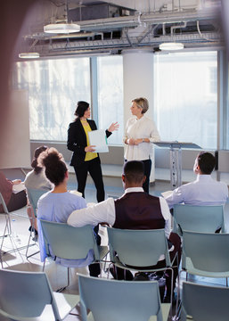 Businesswomen talking, leading conference presentation
