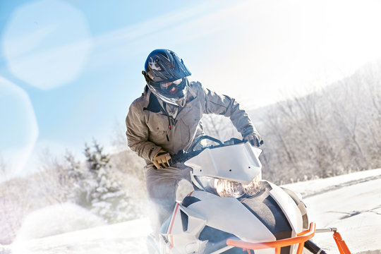 Man riding snowmobile in sunny snowy field