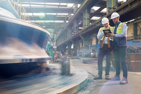 Male foreman and engineer with digital tablet talking in factory