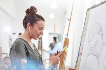 Smiling female artist headphones listening to music sketching in art class studio