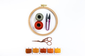 Embroidery accessories. Multicolored bundles of thread, scissors, sewing needles. White background ready for copywriting.