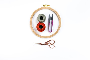 Embroidery accessories. Multicolored bundles of thread, scissors, sewing needles. White background ready for copywriting.