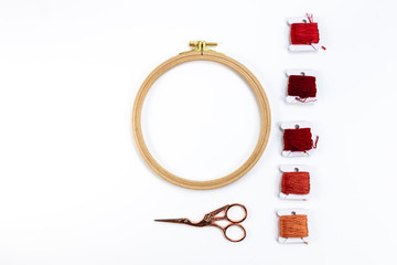 Embroidery accessories. Multicolored bundles of thread, scissors, sewing needles. White background ready for copywriting.