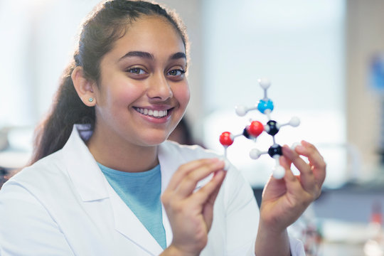 Portrait smiling girl student holding molecular model in laboratory classroom