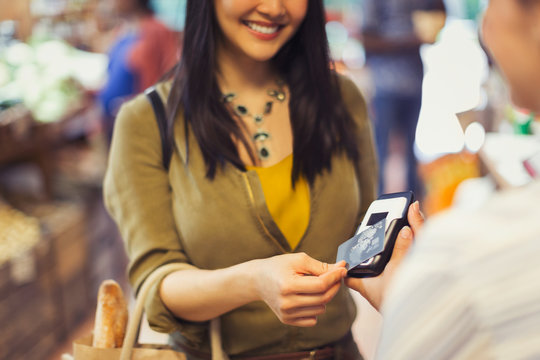 Young Woman Paying Cashier Contactless Credit Card Payment In Store