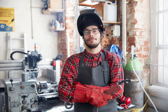 Portrait confident welder with welding torch in workshop