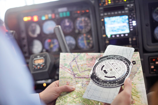 Pilot checking navigational map compass instrument in airplane cockpit