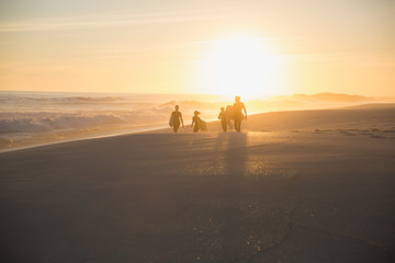 Silhouette family walking on sunny summer sunset beach