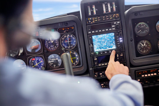 Male pilot using navigational instruments in airplane cockpit