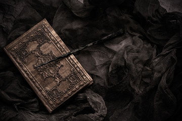 Old book with spells and magic wand on gray background with witch rag. Copy space for text