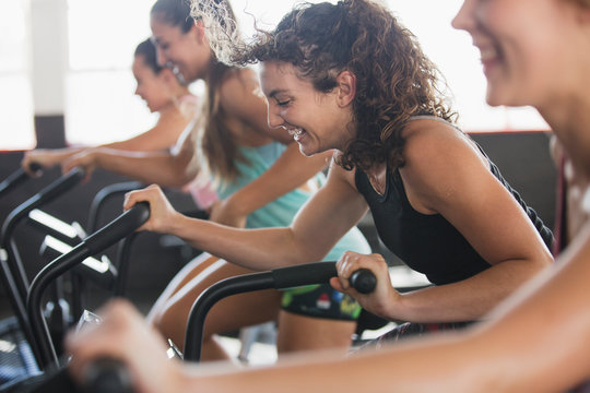 Smiling young woman using elliptical bike in exercise class