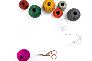 Embroidery accessories. Multicolored bundles of thread, scissors, sewing needles. White background...