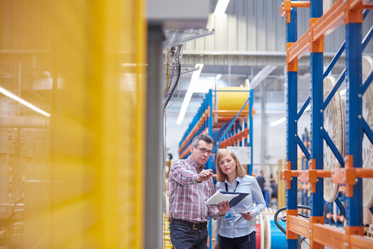 Male female managers with clipboard talking in fiber optics factory