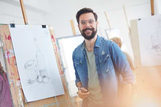 Portrait smiling male artist with beard sketching in art class studio