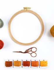 Embroidery accessories. Multicolored bundles of thread, scissors, sewing needles. White background ready for copywriting.