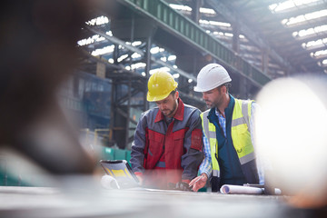 Male engineers using laptop in factory
