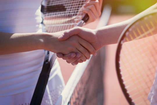 Close up tennis players handshaking in sportsmanship at net