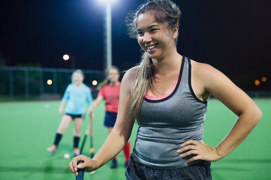 Smiling young female field hockey player on field