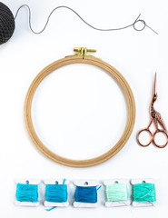 Embroidery accessories. Multicolored bundles of thread, scissors, sewing needles. White background ready for copywriting.