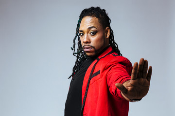 Closeup studio portrait of a man wearing a red jacket suit and dreadlocks