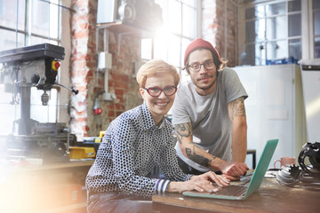 Portrait confident designers working at laptop in workshop