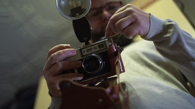 Young bearded guy uses a vintage camera. Looking at old photos. The camera F30-5v was produced by the Kharkiv Production Engineering Association "FED" from 1975 to 1991.