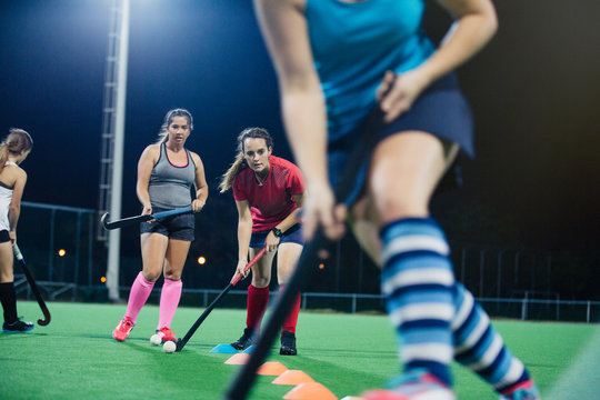 Young female field hockey players practicing sports drill on field
