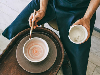 Ceramist at a pottery workshop Top view photo Man is glazing a ceramic plate at rotating potter's...