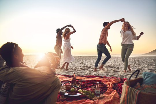 Young couples dancing, enjoying picnic on summer beach