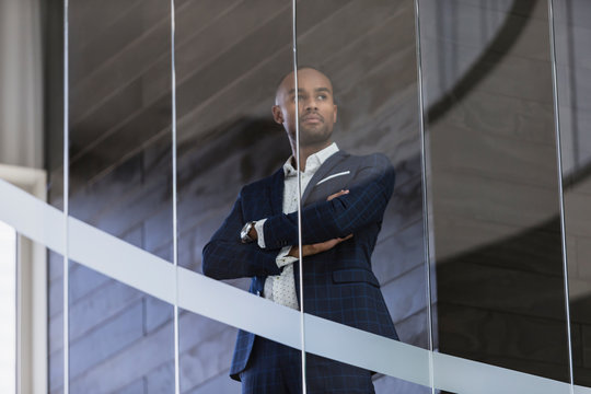 Serious, CEO businessman standing at office window