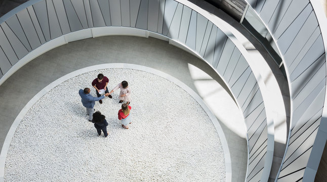 View from above business people handshaking in round modern office atrium courtyard