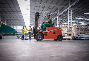 Male worker driving forklift in factory