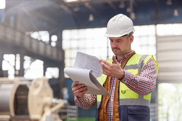Male foreman reviewing paperwork on clipboard in factory