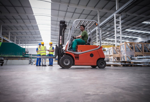 Male worker driving forklift in factory