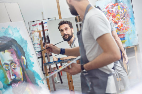 Male artists painting in art class studio