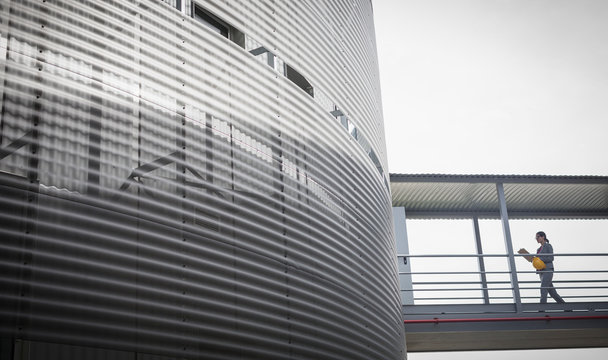 Female supervisor walking on elevated walkway connected to building