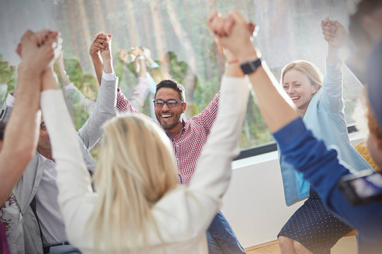 People smiling and holding hands in circle in group therapy session