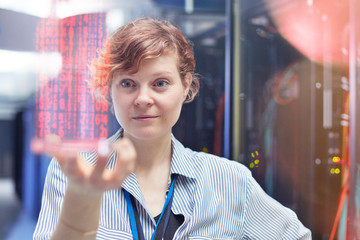 Female IT technician holding futuristic digital tablet in server room
