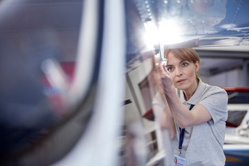Focused female engineer mechanic examining airplane