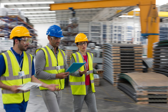 Supervisor and workers with clipboard and digital tablet walking in factory
