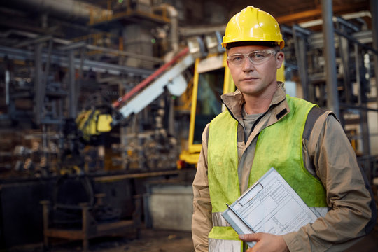 Portrait serious, confident steelworker with clipboard in steel mill