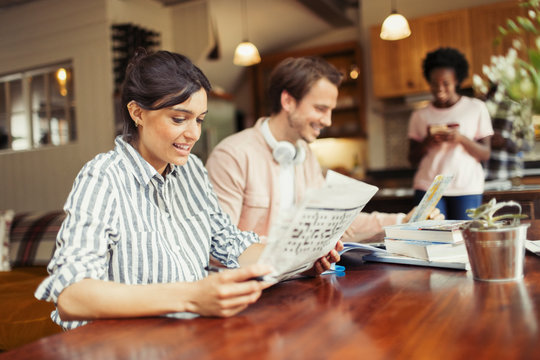 Woman reading newspaper at dining table