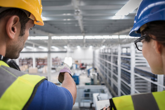 Supervisors talking and pointing on platform in factory