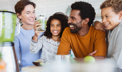Smiling multi-ethnic family drinking healthy green smoothie in kitchen