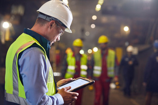 Steelworker using digital tablet in steel mill