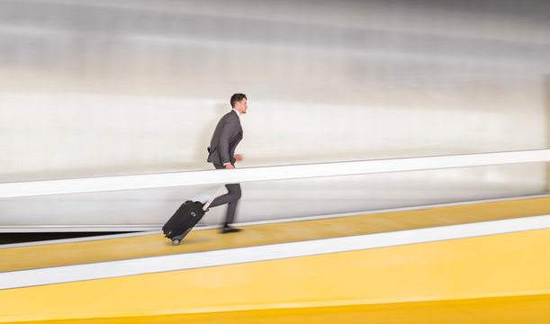 Businessman running, pulling suitcase up airport ramp